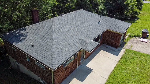 Brick ranch: A brick ranch with a new grey shingle roof and gutters along the eaves.