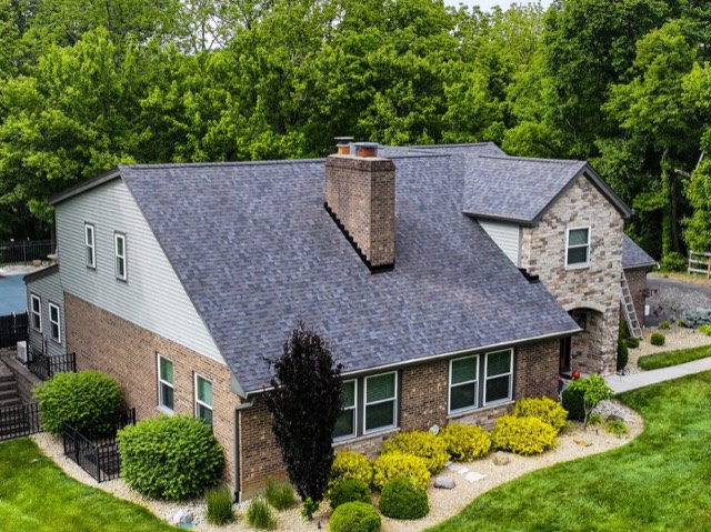 Brick and stone home: New dark architectural shingles across a hip and gable roofline.